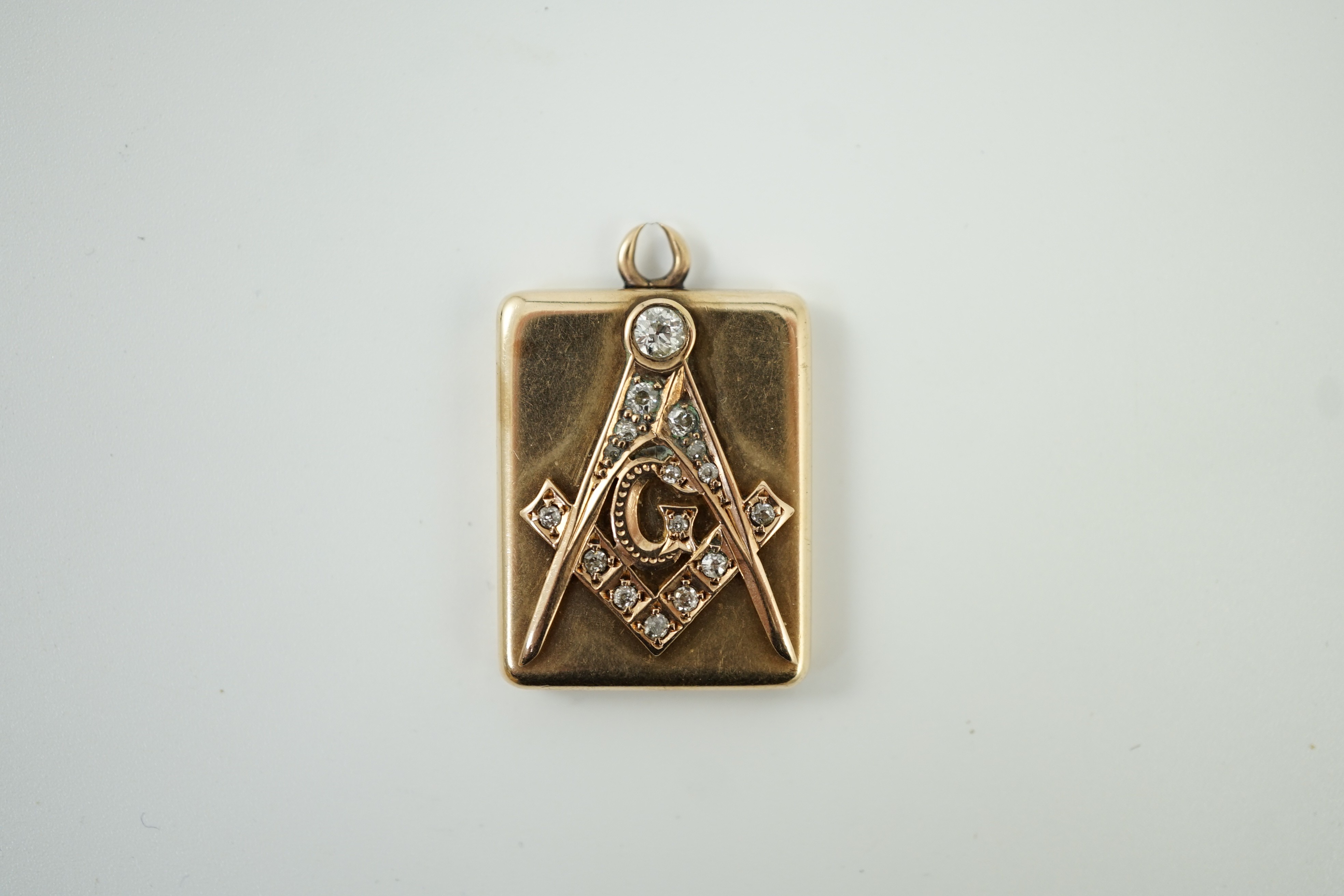 An Edwardian yellow metal and diamond cluster set masonic locket pendant, with engraved inscription verso 'Presented to Henry Drucker by Wm. McKinley', overall 33mm, gross weight 12.3 grams.